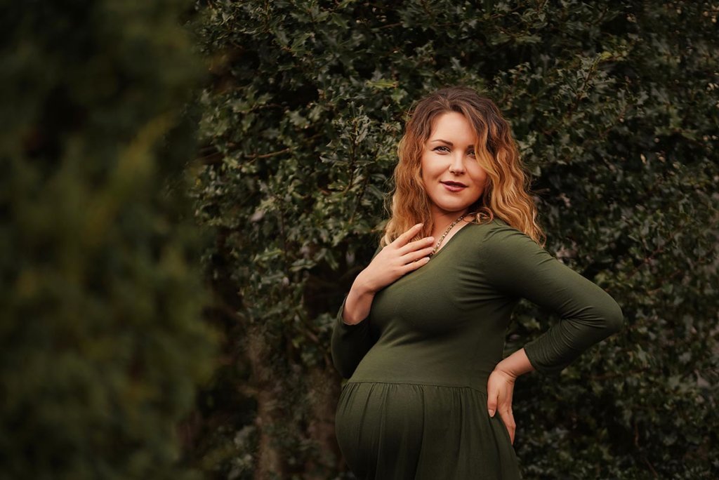 Schwangere Frau im grünen Kleid bei einem Outdoor Babybauch Shooting