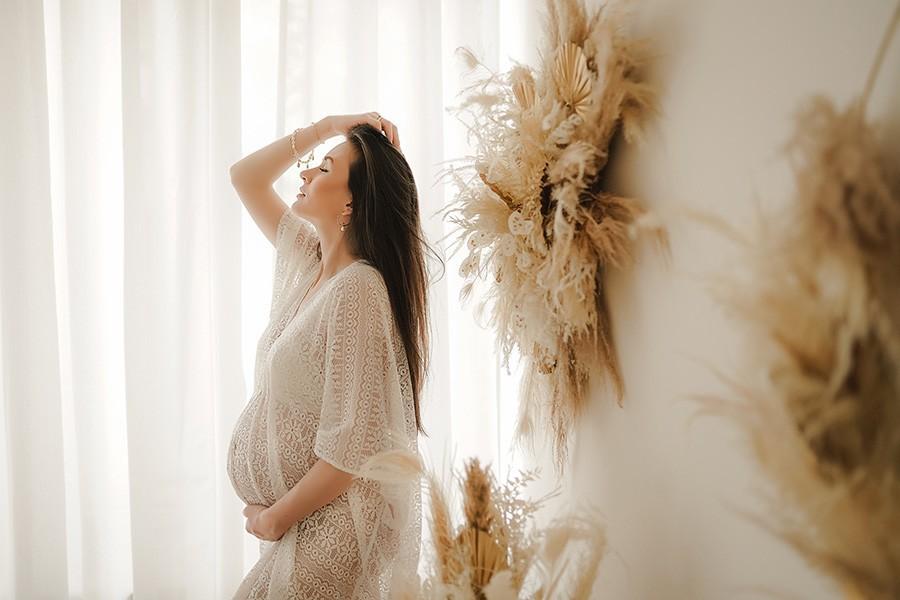 Unvergessliche Schwangerschaftsfotos von einer dunkelhaarigen Frau im weißen Kleid, entstanden bei einem Babybauch Shooting im Fotostudio von Lucky Memory Photography in München