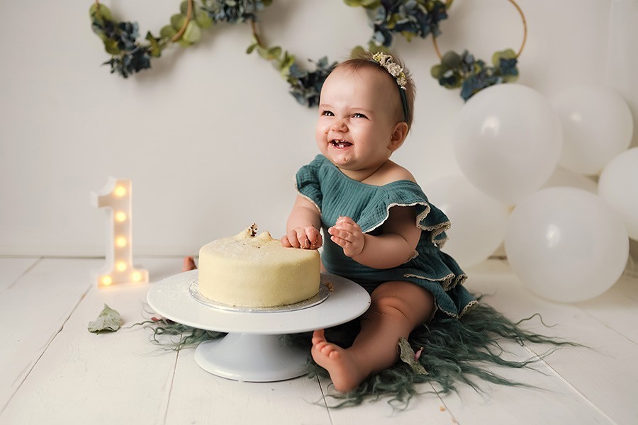 Süsses Kind beim Torten essen während Cake Smash Shooting zu ersten Geburtstag in Fotostudio München